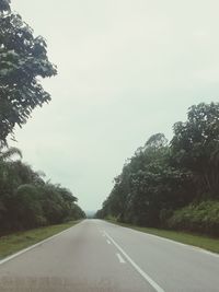 Empty road amidst trees against sky