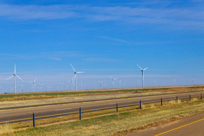 Wind turbines on field against sky