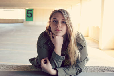 Portrait of young woman leaning on railing at parking lot