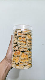 Close-up of hand holding food in glass against white background