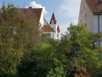 Low angle view of trees and building against sky