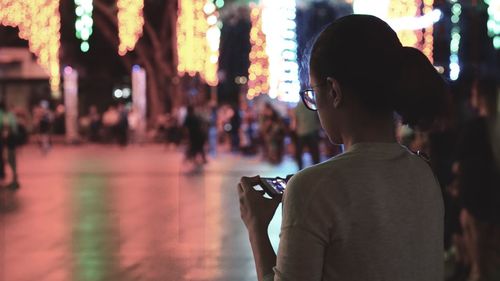 Woman using mobile phone in illuminated city