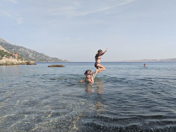 Two childrenplaying and jumping in the sea