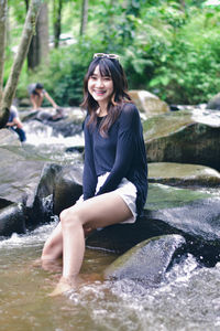 Portrait of young woman sitting in river