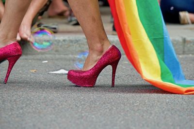 Low section of woman with rainbow flag standing on street