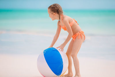 Rear view of woman with arms raised standing at beach