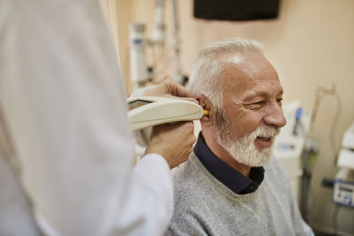 Ent physician examining ear of a senior man