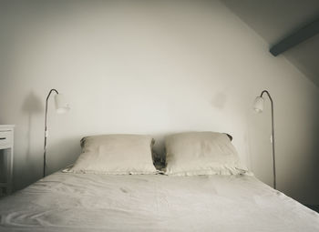 Empty bed against white wall at home