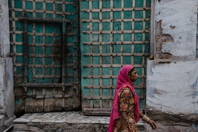 Side view of woman standing against old building