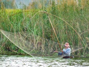 Woman sitting on fishing net in lake