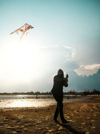 Rear view of woman standing on beach against sky