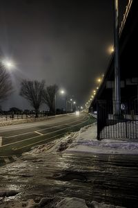 Illuminated street lights on road in winter at night