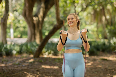 Woman working out with elastic rubber bands at a park outdoors. athlete female healthy, exercise .
