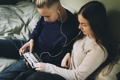 High angle view of teenage friends using sound mixer at bedroom