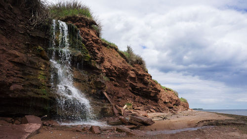 Scenic view of waterfall against sky