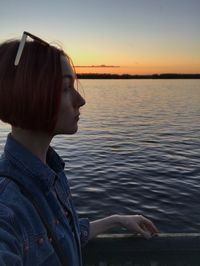 Side view of young woman against sea during sunset