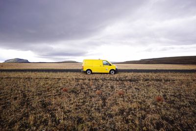 Yellow car on field against sky