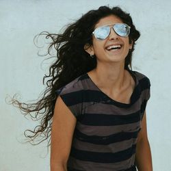 Portrait of young woman wearing sunglasses standing against white background