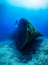 Scuba diver by shipwreck in sea