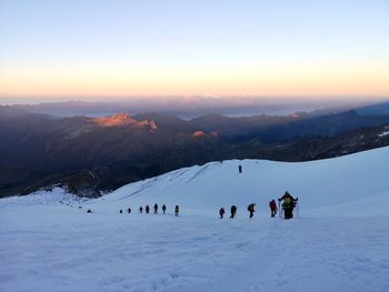 Group of people on snowcapped mountain against sky