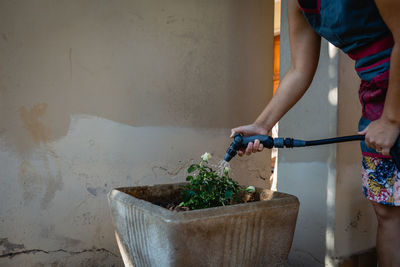 Close up of woman hand watering flowers in a pot in house garden