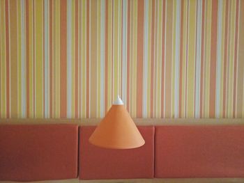 Close-up of electric lamp hanging against sofa and wall