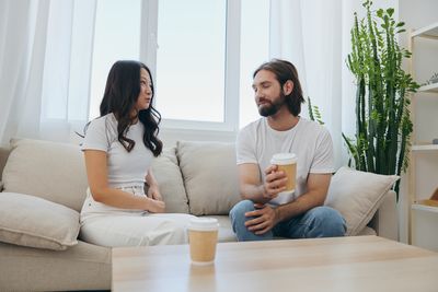 Friends using laptop while sitting on sofa at home