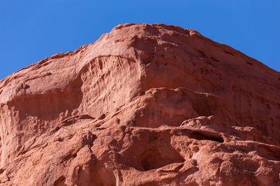 Low angle view of rock formation against clear blue sky