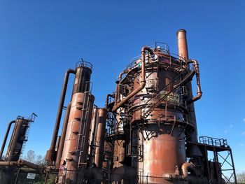 Low angle view of factory against clear blue sky