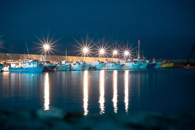 Sailboats moored in sea against sky at night