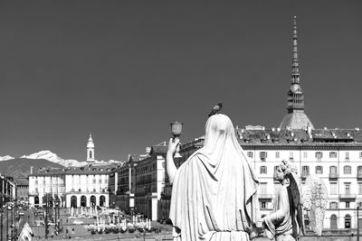 Rear view of statue against buildings in city