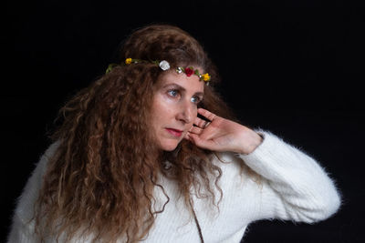 Portrait of young woman against black background