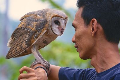 Close-up of man holding owl on hand