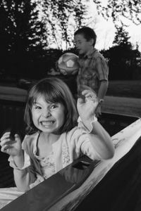 Portrait of playful girl with brother in pick-up truck at park