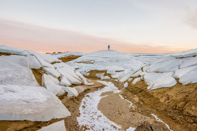 Scenic view of frozen landscape against sky during winter