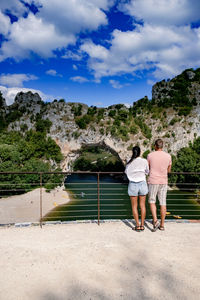 Rear view of couple standing on water against sky