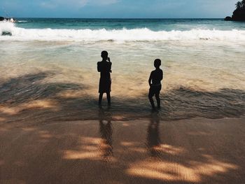 People standing on beach against sky