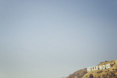 Low angle view of hollywood sign on mountain against clear blue sky