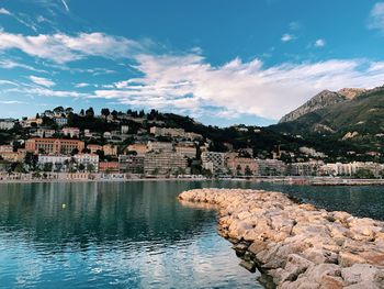 Town by lake in city against sky