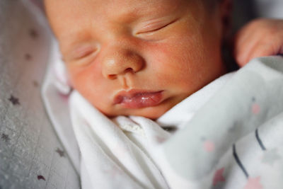 Newborn baby sleeps peacefully. gentle innocent baby lies on light baby cocoon, closeup