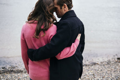 Couple embracing each other at thames riverbank, london, england