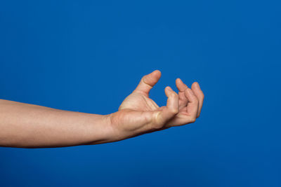 Cropped hand of woman against clear blue sky