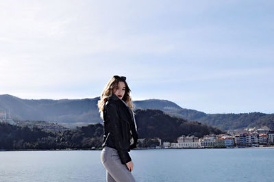 Young woman standing on mountain against sky