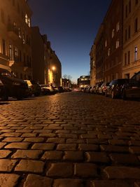 Cobblestone street amidst buildings in city at night