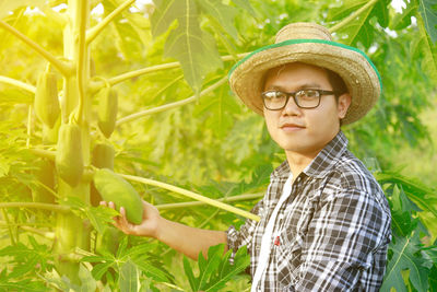 Portrait of young man with papaya plant