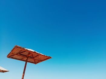 Low angle view of parasol against clear blue sky