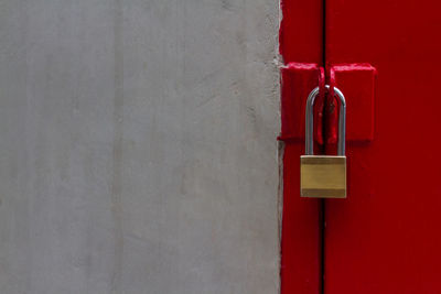 Textured of old dark cement wall and brass pad lock with strong gate red slide door and copy space.