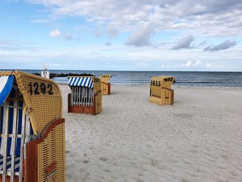 Hooded chairs on beach against sky