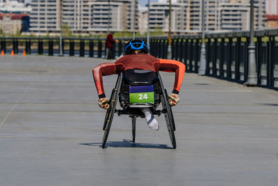 Rear view of man riding push scooter on street