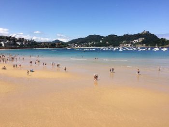 People swimming in sea against blue sky